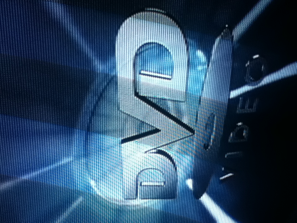 The DVD Video logo on a TV screen, glowing blue with light rays behind it, the screen’s scanlines visible